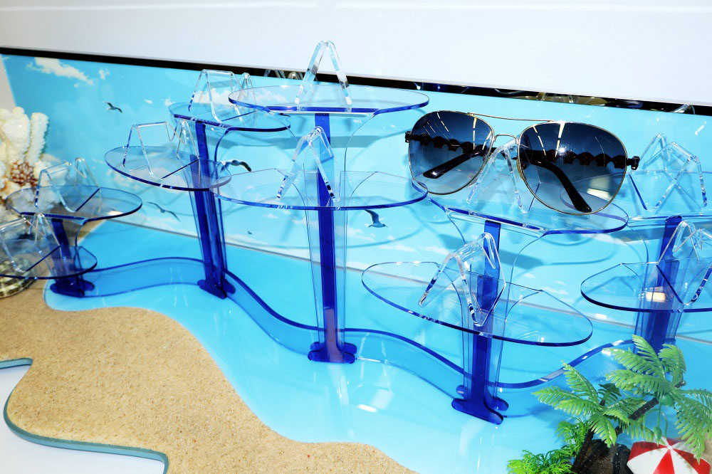 High angle close-up of complete coastal sunglasses display showing multi-level tiered layout